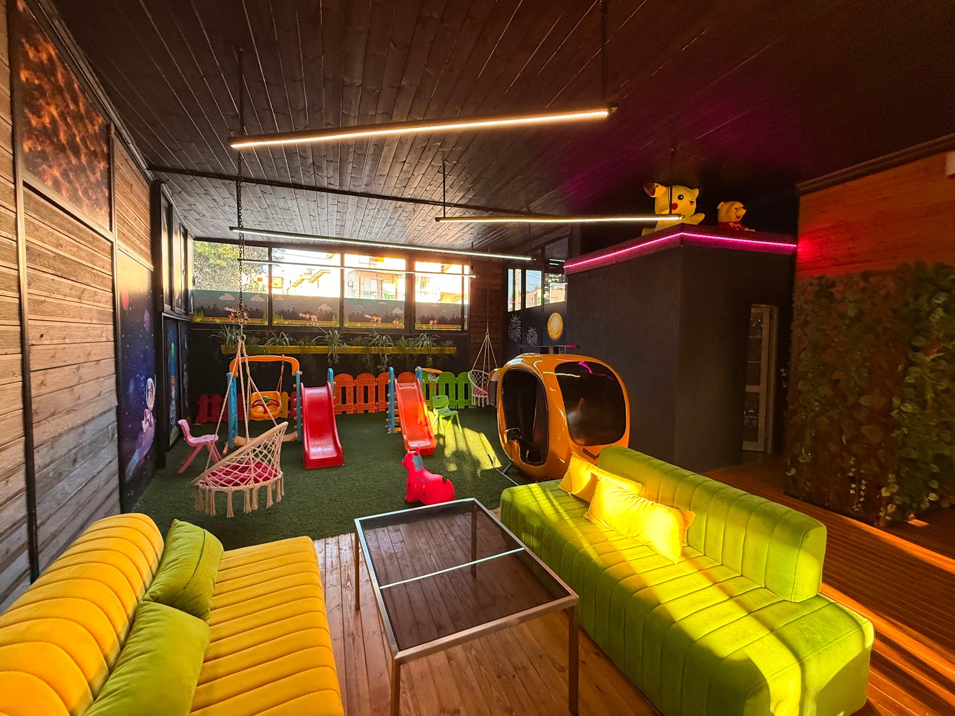 Lounge familjar me divane jeshile pranë këndit të lojërave